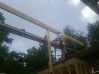 Carpenter setting a ridge beam over a new addition frame — Ice Dam Removal by Roofing Brothers in Oklee