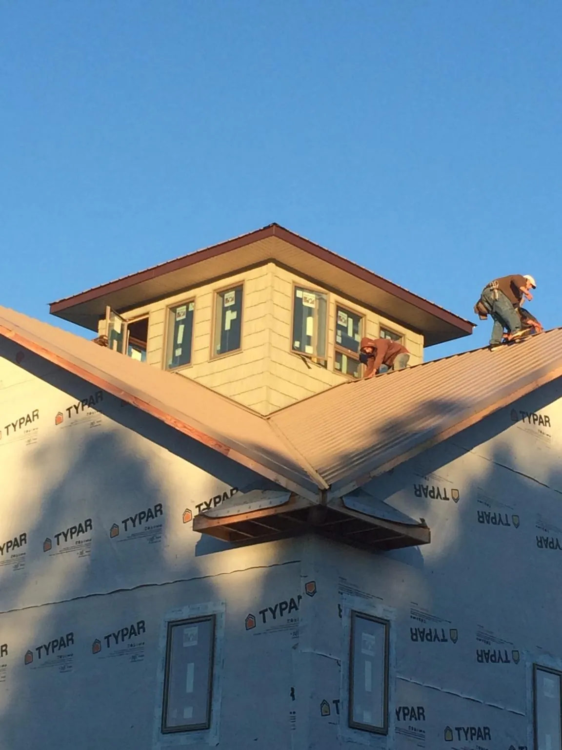 Roofers working around a rooftop cupola on a new metal roof at sunset — Roof Waterproofing in Oklee by Roofing Brothers